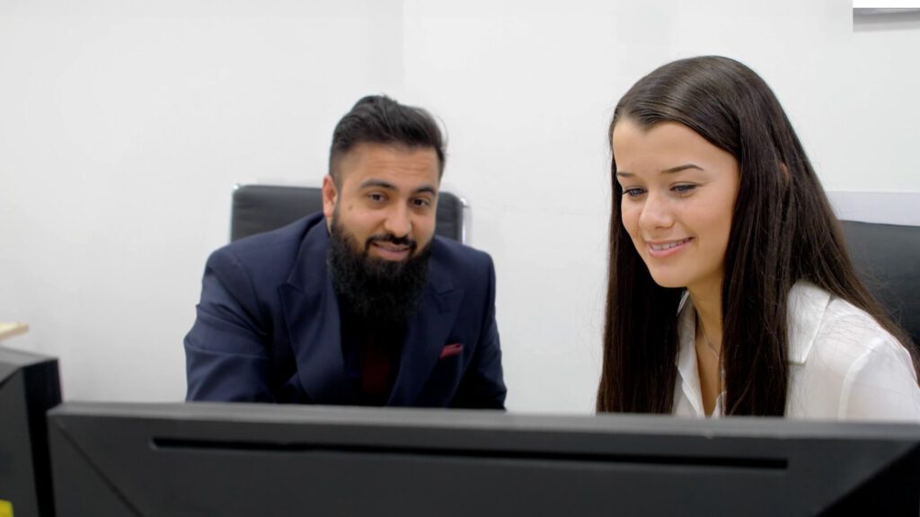 An employer interacting with an apprentice using a desktop computer.