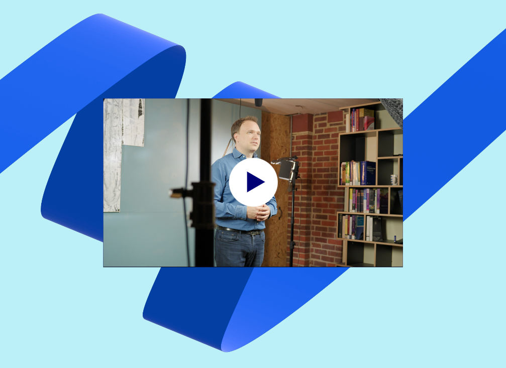 Image of the Managing Director of Mindful Education, in a studio filming videos for the Virtual Learning Environment on a light blue background with dark blue ribbon.