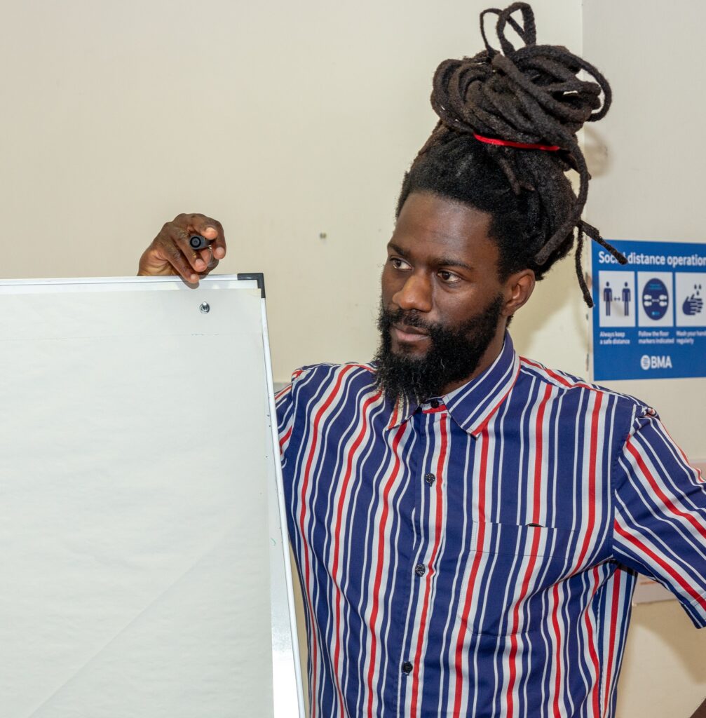 A Mindful Education apprentice stood next to a whiteboard and listening to ideas from fellow team members about how to improve the learner experience.