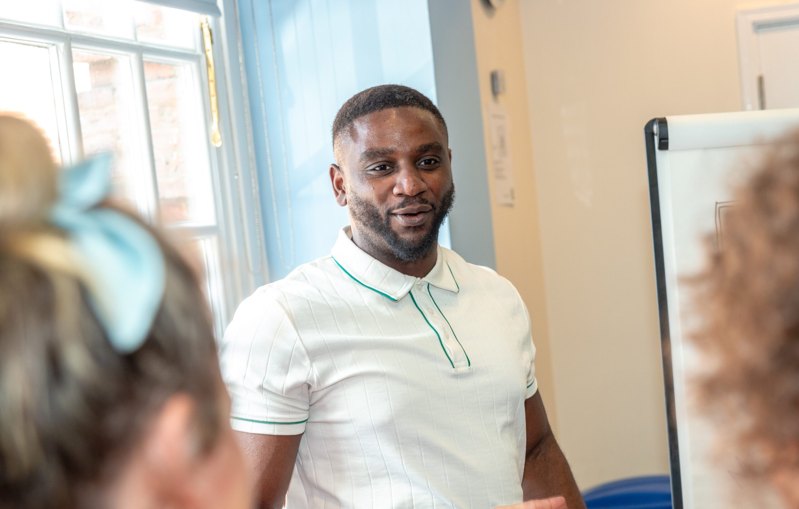 A Mindful Education apprentice, smiling whilst presenting ideas about streamlining internal operations at a company gathering.