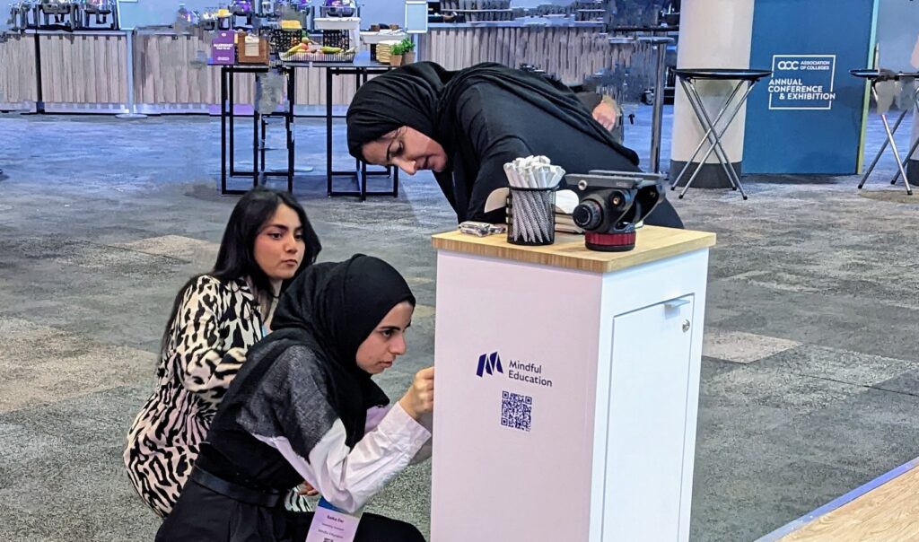 Three Mindful Education employees applying sticker QR codes to a podium.