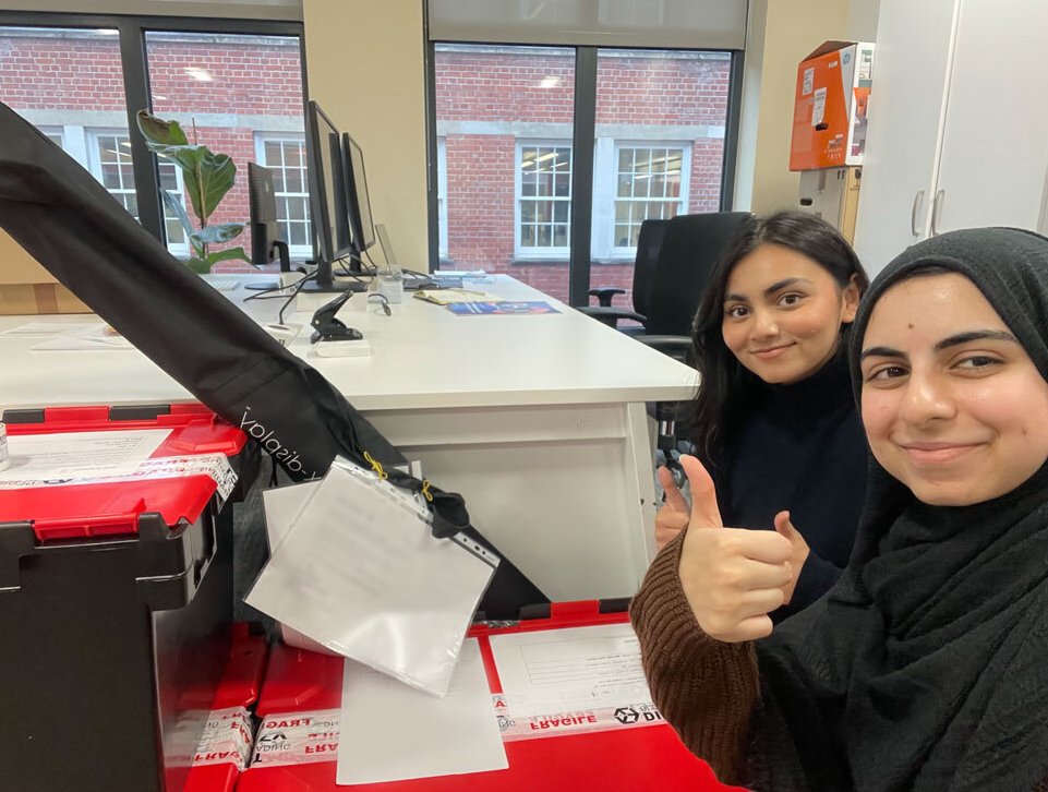 A selfie of two Mindful Education employees in front of large crates.