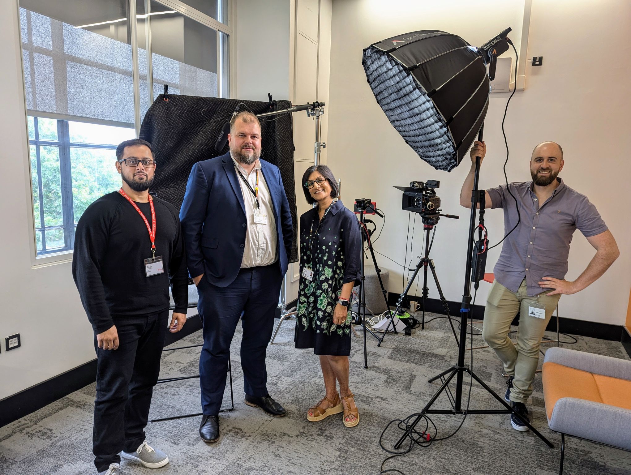 A Mindful Education employee standing alongside three individuals from Activate Learning in a room filled with various pieces of filming equipment.