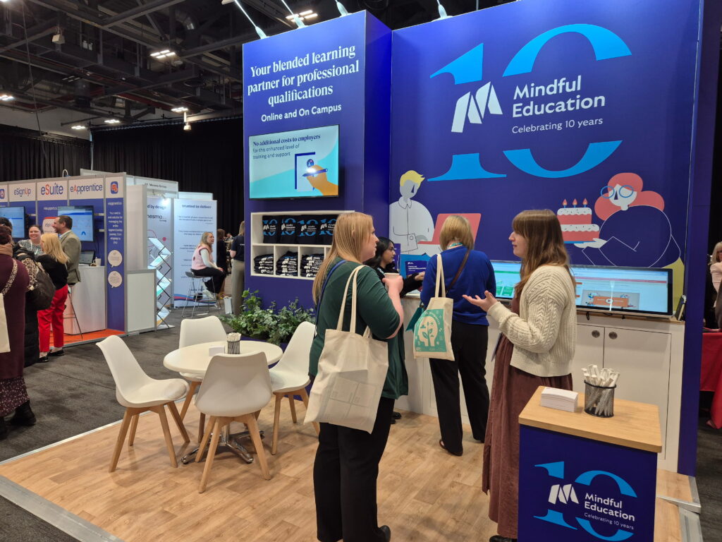 An image of the Mindful Education team at an industry event, speaking to learners and senior leaders in further education about professional apprenticeships.